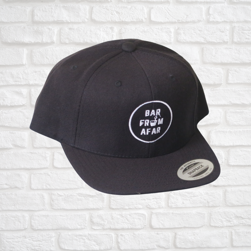 Black flat brim cap with bar from afar logo stitched in the front of hat with white stitching 