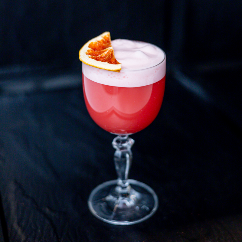 Bitter Bus Cocktail - whiskey, Italian bitters, grapefruit, , strawberry, lime, egg white in Nick and Nora glass, garnished with dehydrated grapefruit 