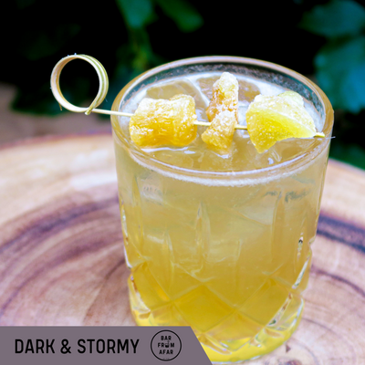 Dark and stormy cocktail in a glass with ginger candy